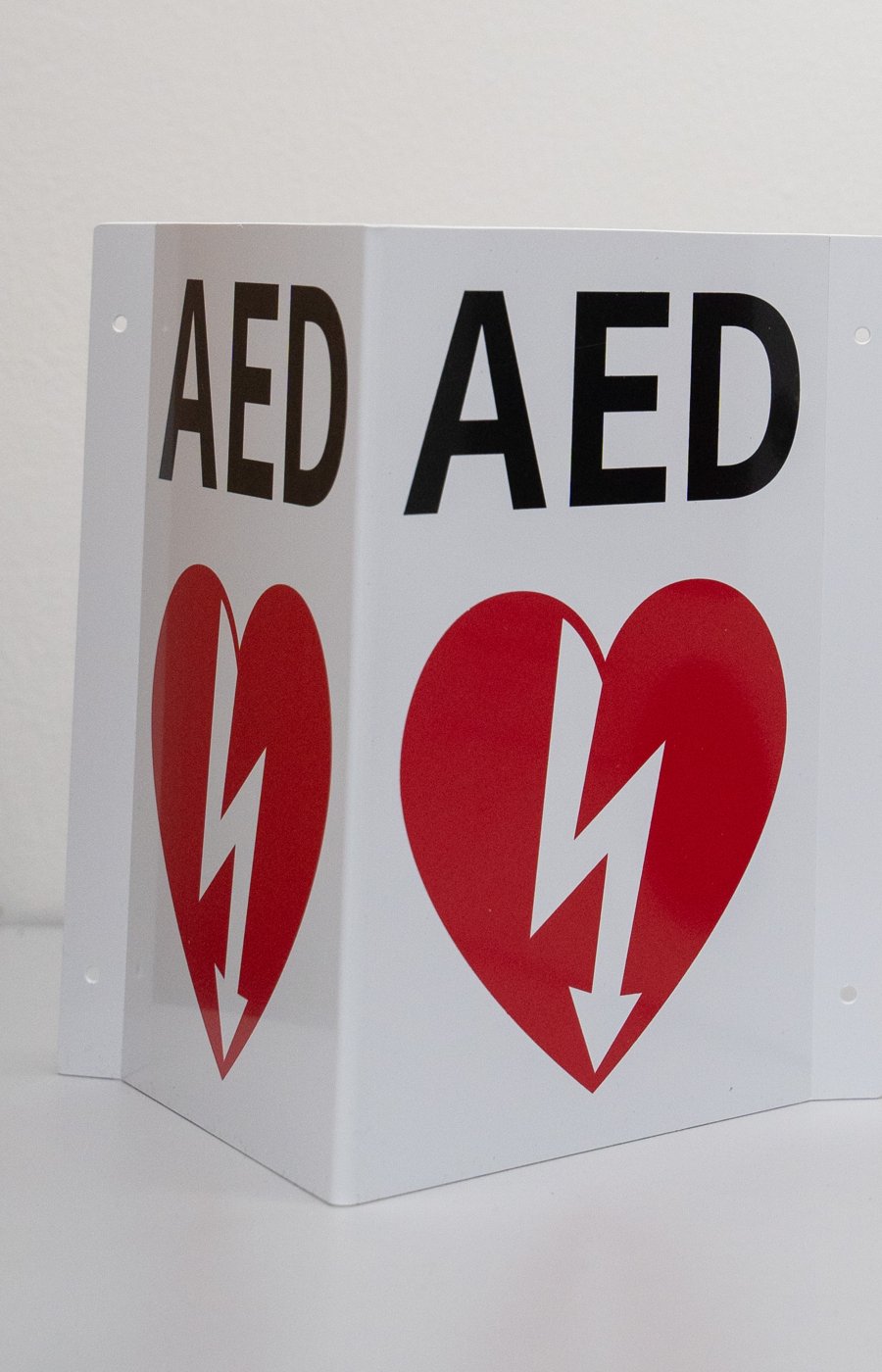 Two-sided wall-mounted AED sign with heart and lightning symbol
